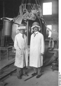 Prof. Piccard wieder fertig zu seinem grossen Stratosphären-Flug! Der Brüsseler Prof. August Piccard (rechts) und sein Begleiter, der Schweizer Ing. Kipfer (links) mit ihrem aus Nähkörben verfertigten Sturzhelmen vor der Kugel, fertig zum Stratosphärenflug in 16.000 m Höhe.